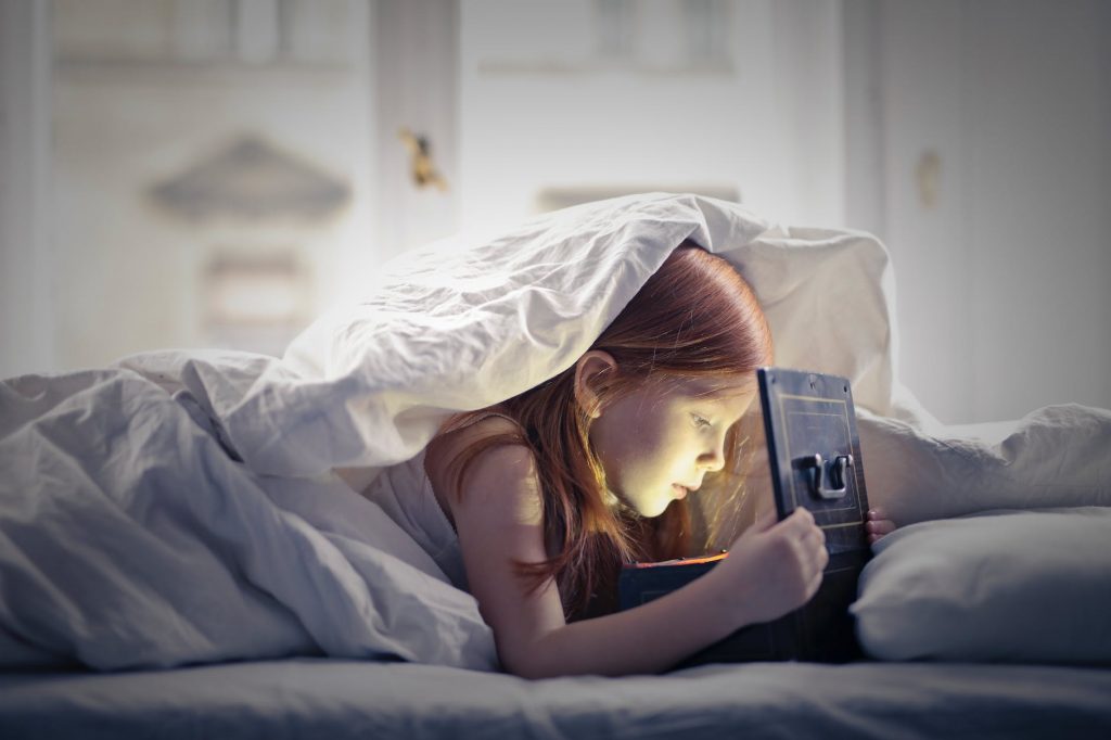 girl on bed looking at an open lighted box